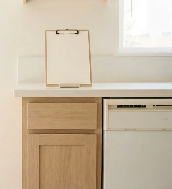Clipboard on a kitchen counter above an older white dishwasher